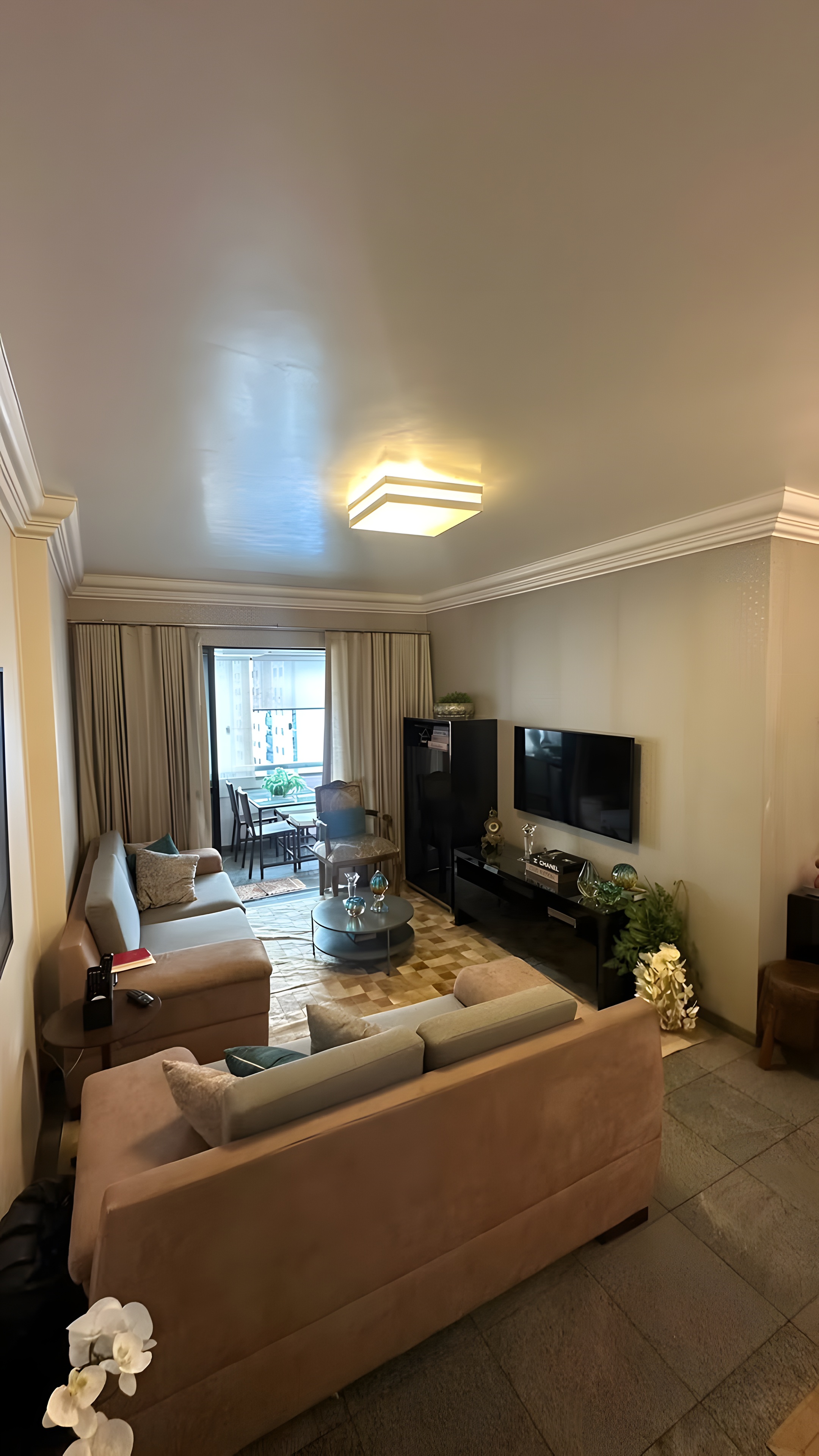 Estar existente com sofás em suede, rack escuro e TV