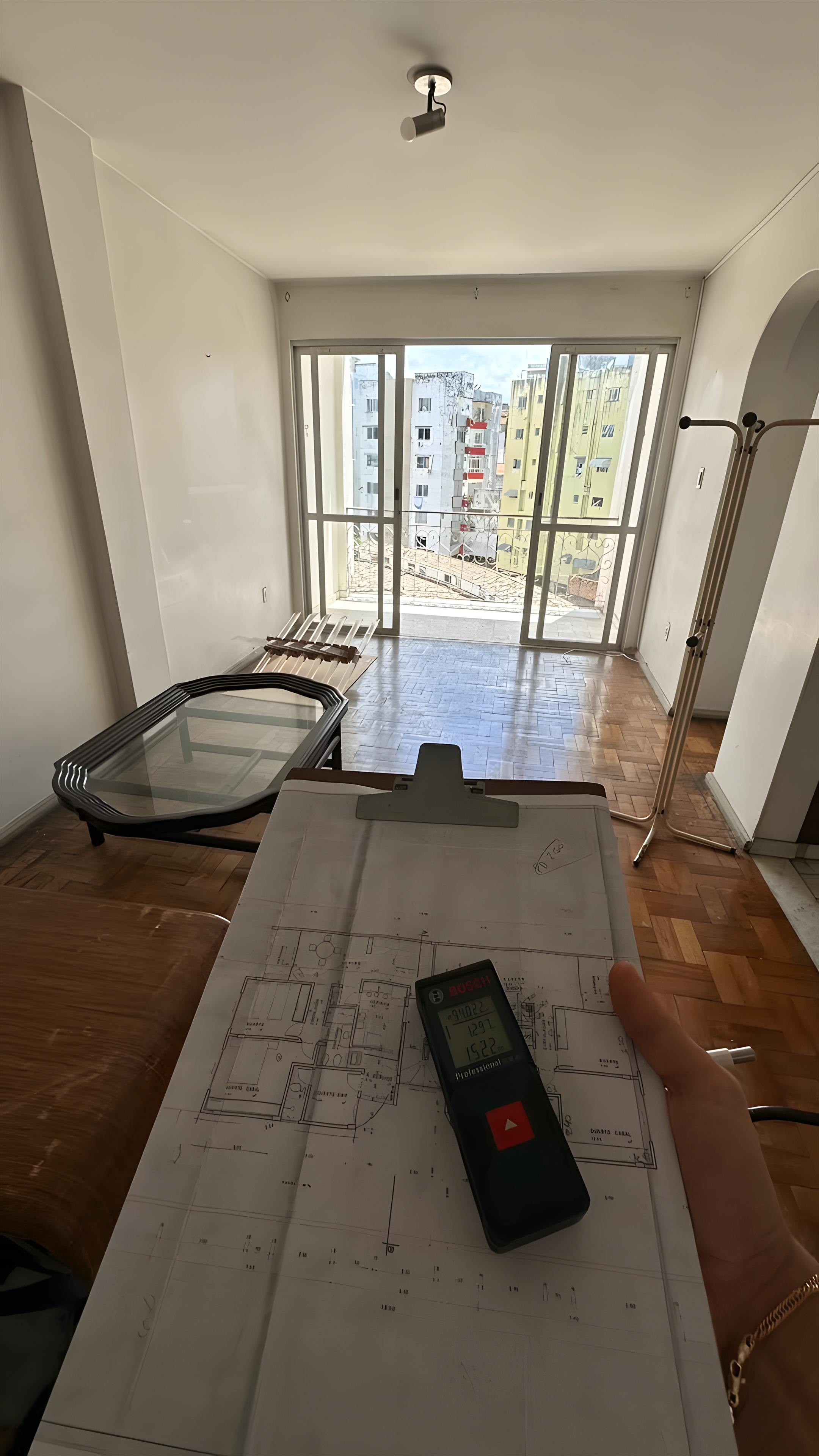Levantamento no local: planta impressa e trena a laser na sala com varanda