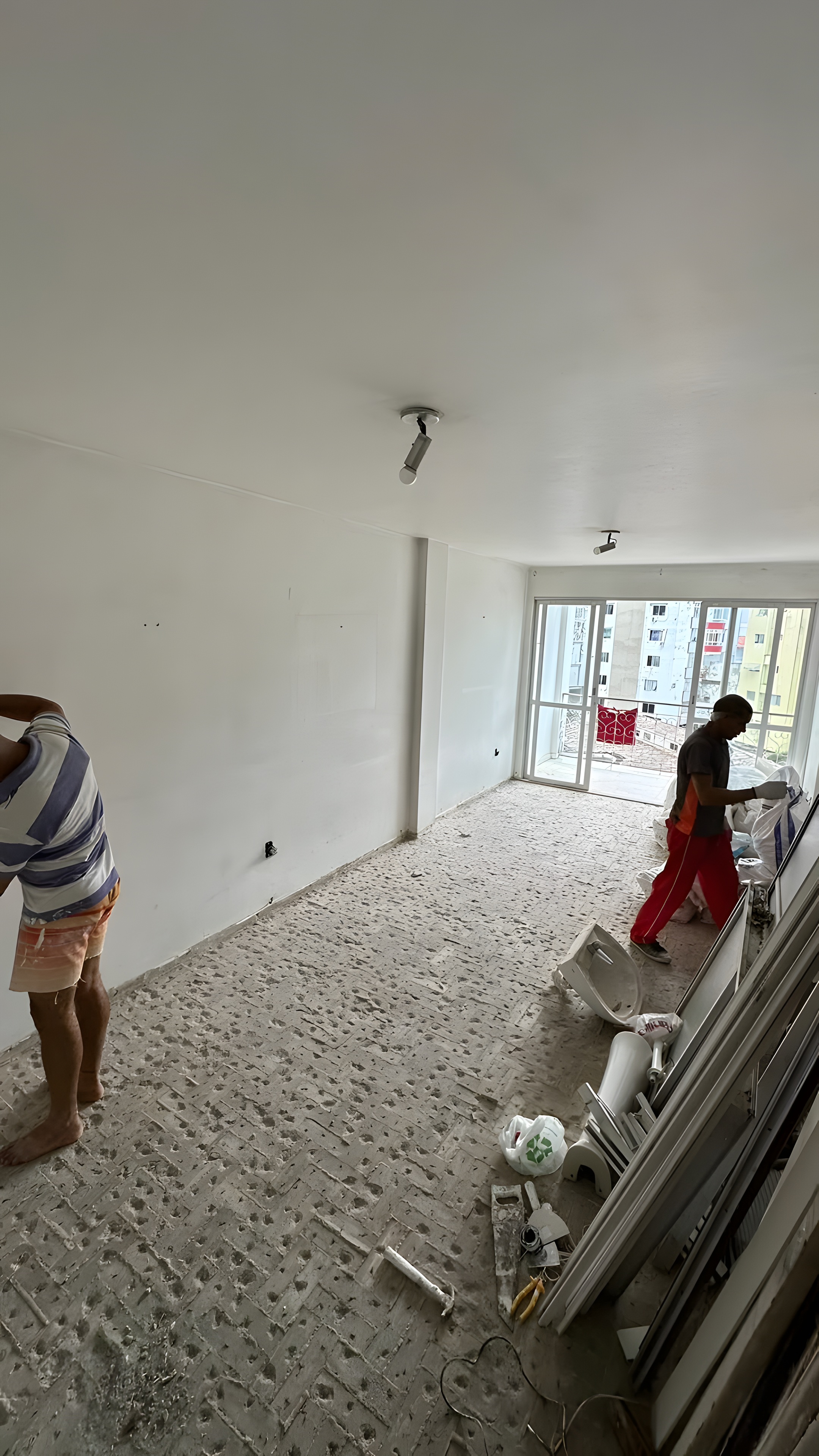 Sala em obra com equipe trabalhando e piso removido