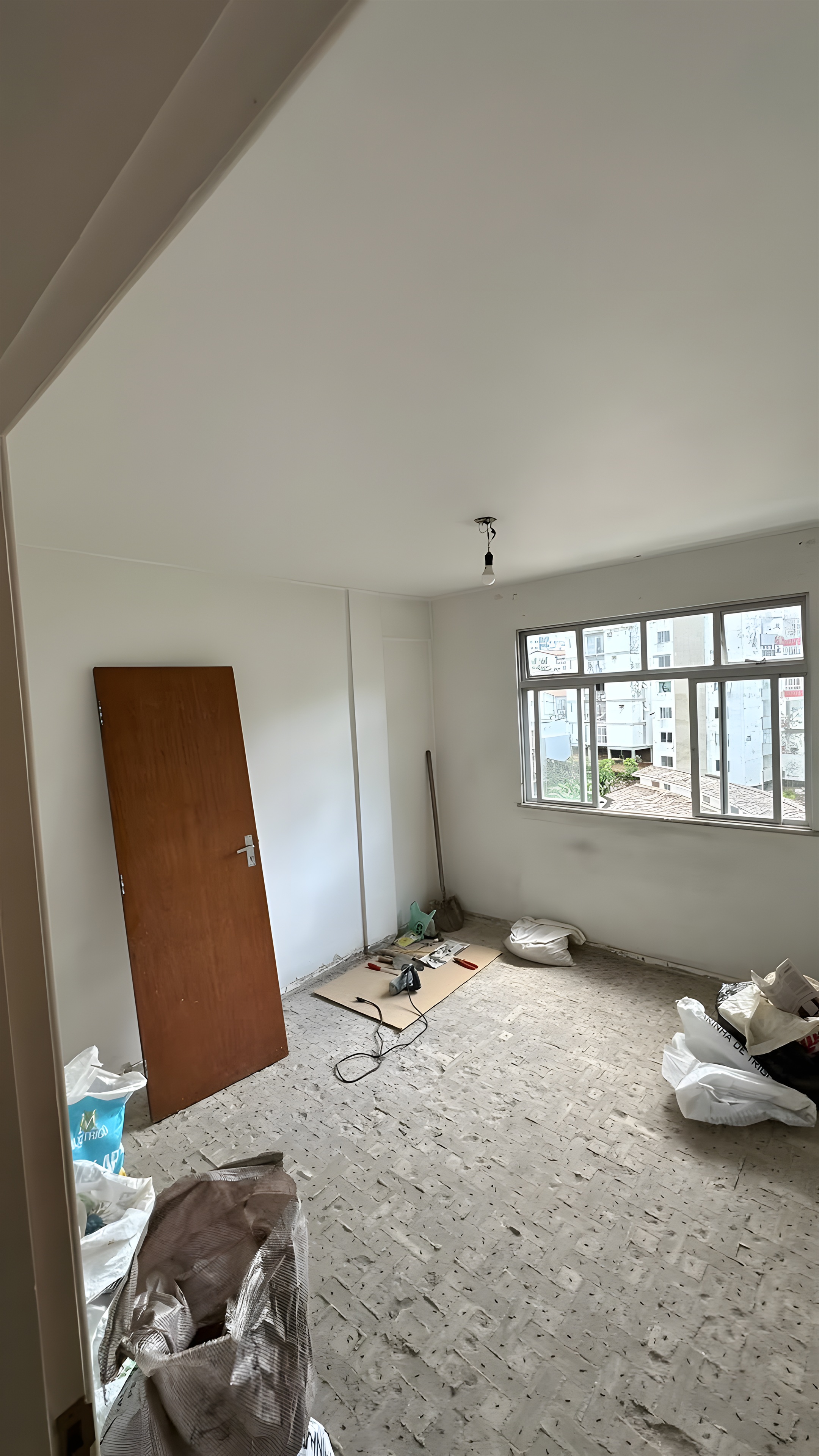 Quarto existente com porta em madeira retirada e piso em obra